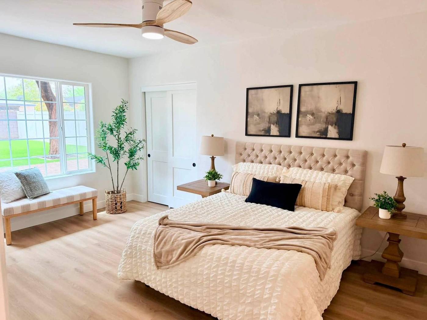 Bedroom staged with a tufted headboard, layered bedding and a window bench