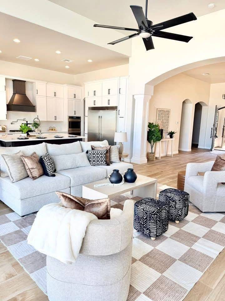 Great room open to the kitchen, staged with a checkerboard rug and boucle seating Great room open to the kitchen, staged with a checkerboard rug and boucle seating