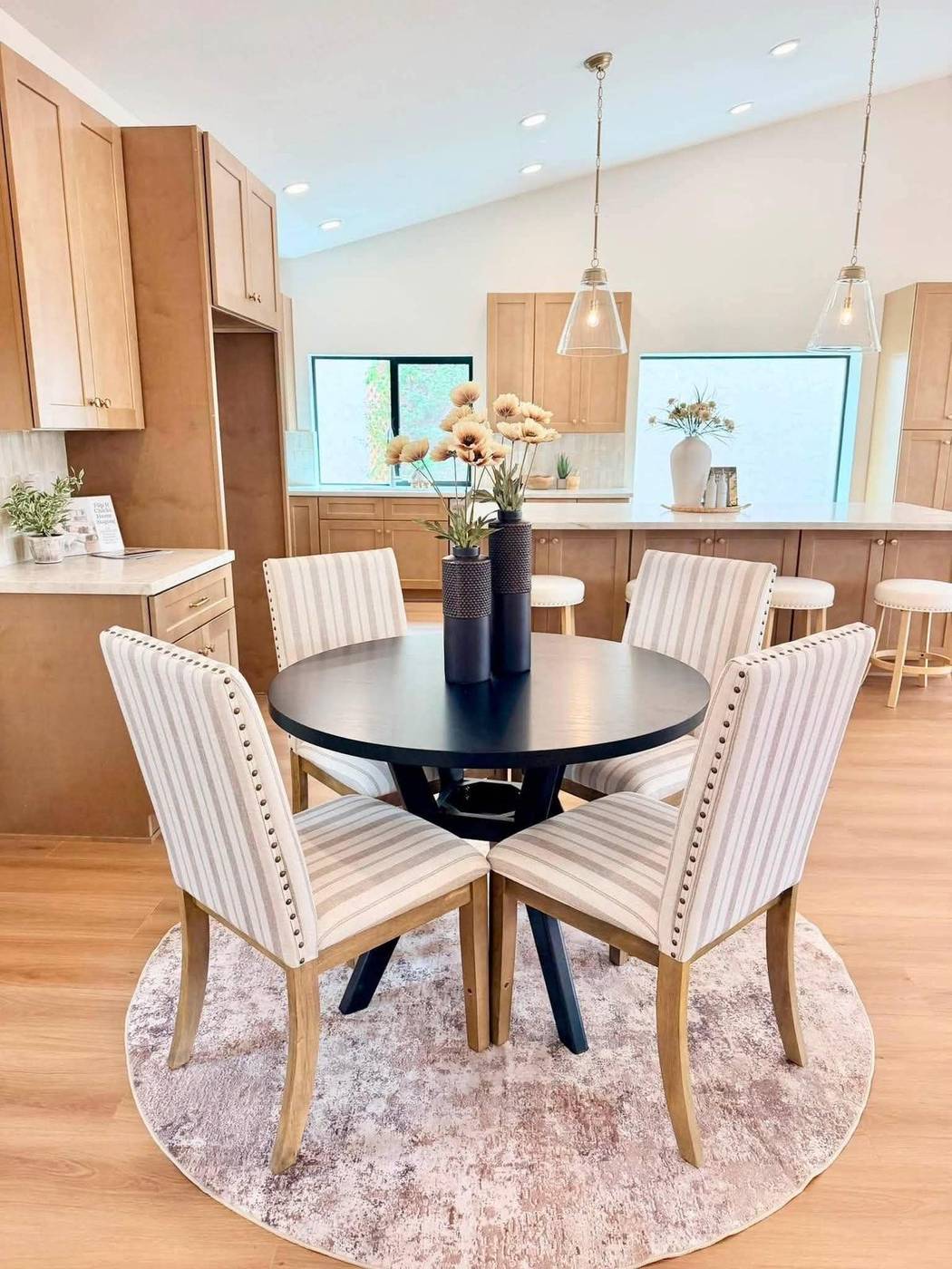 Breakfast nook staged with a round black table, upholstered chairs and a round rug
