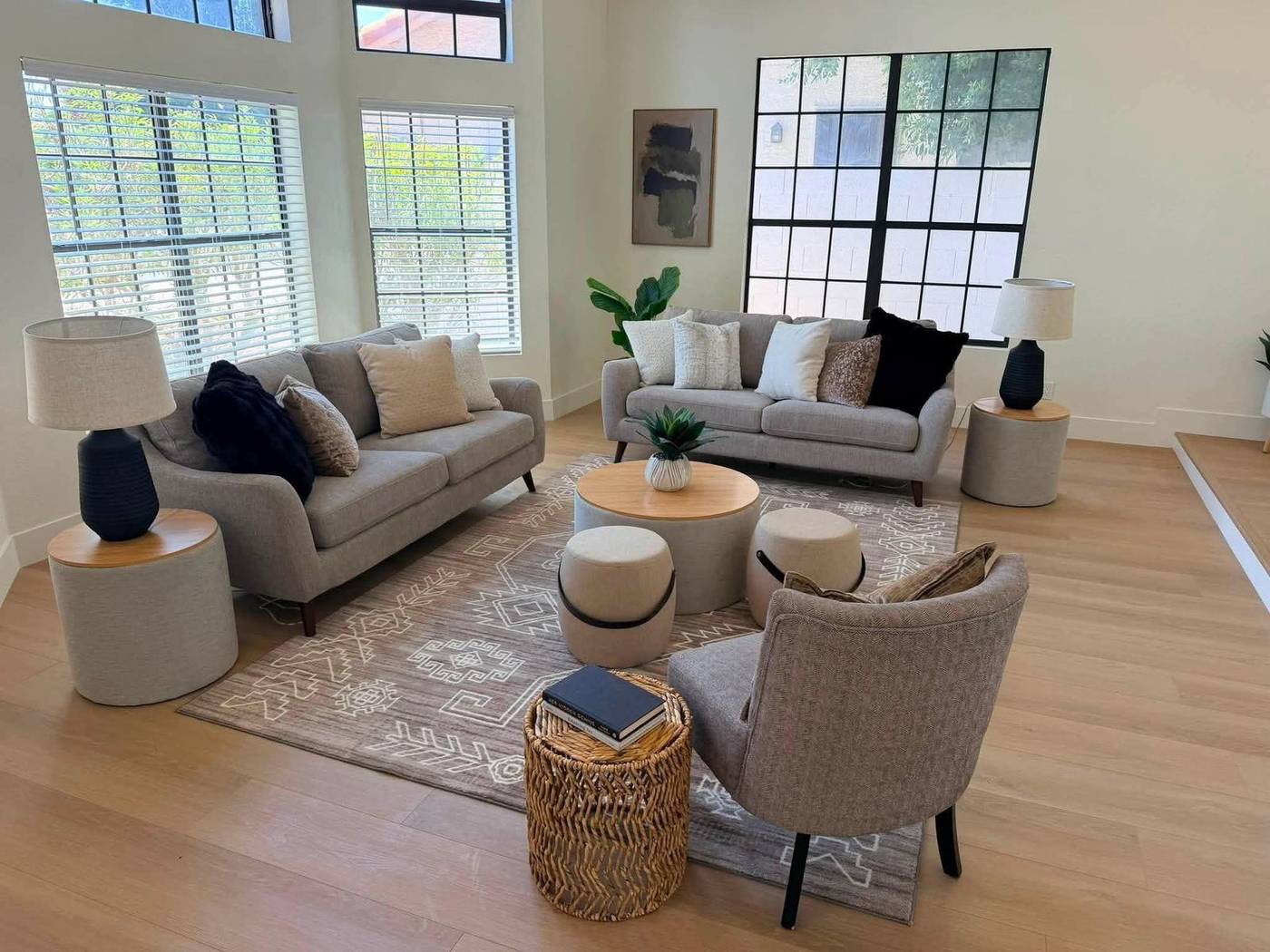 Two-story living room staged with paired sofas, swivel chairs and a neutral rug
