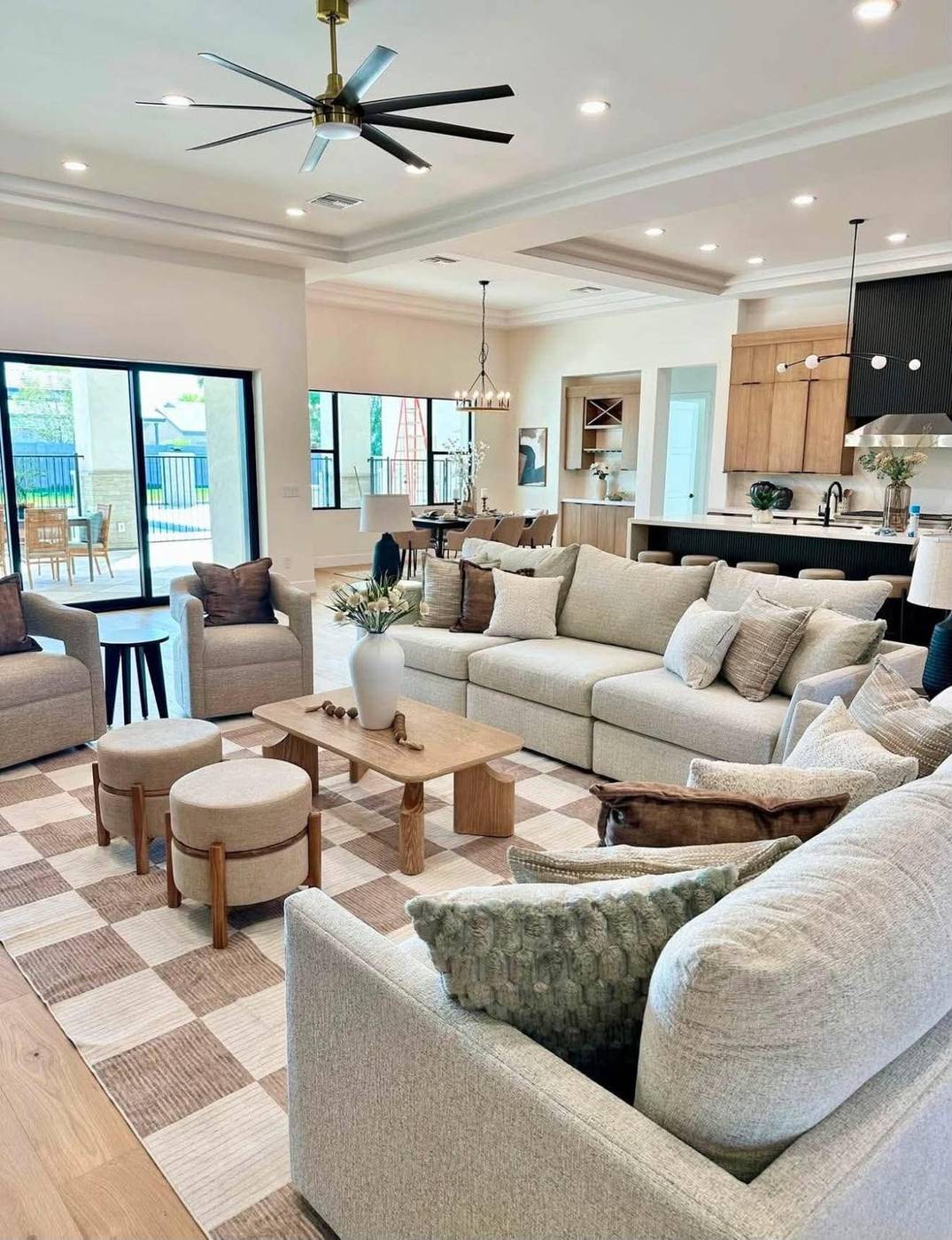 Coffered-ceiling great room staged with a long sectional and paired ottomans Coffered-ceiling great room staged with a long sectional and paired ottomans
