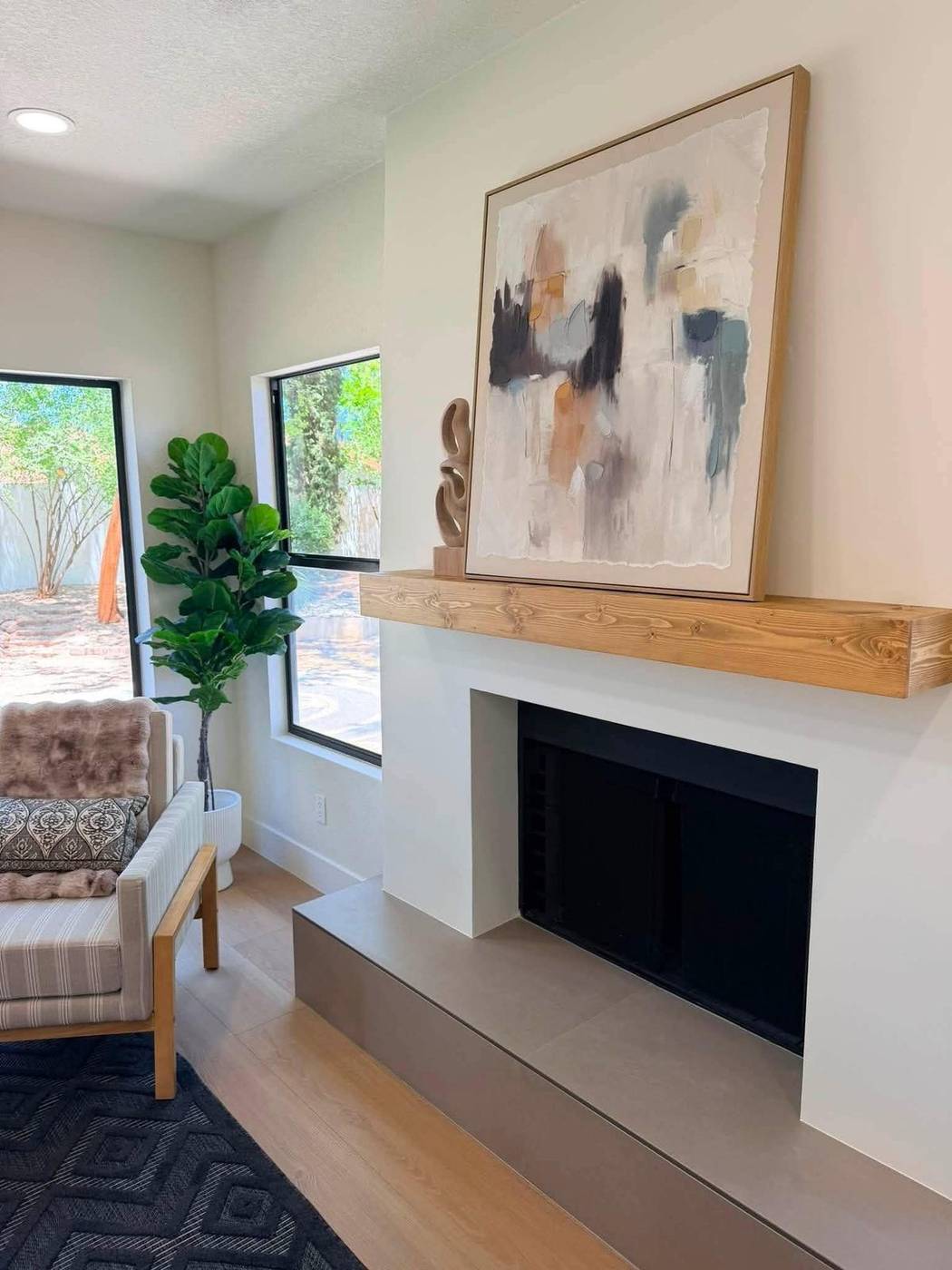 Fireplace styled with a reclaimed wood mantel and abstract art above