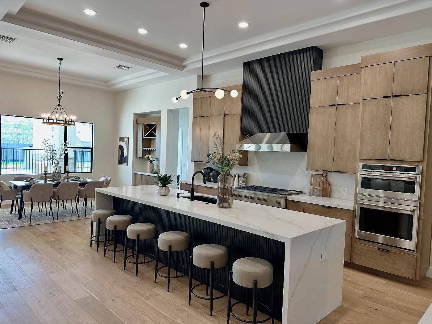 Oversized kitchen island staged with barstools and a dining table beyond