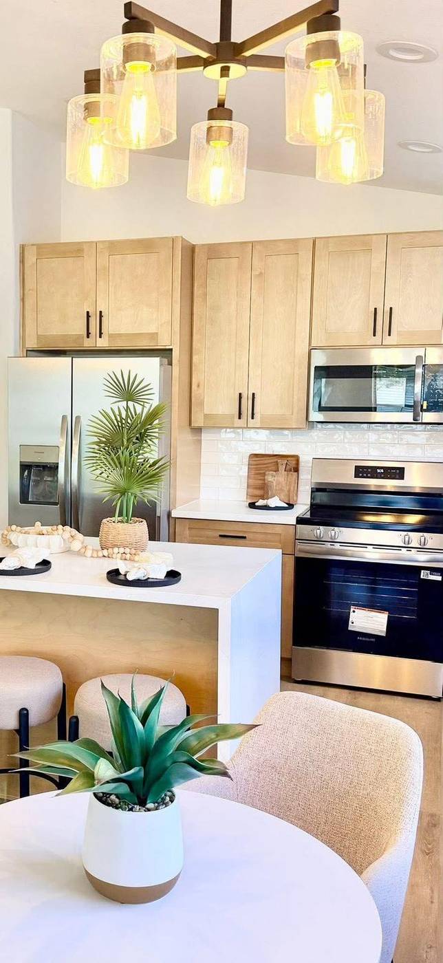 Light wood kitchen staged with a round dining table and greenery centerpiece