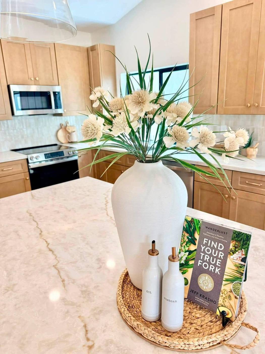 Kitchen counter vignette with a white ceramic vase, florals and a cookbook